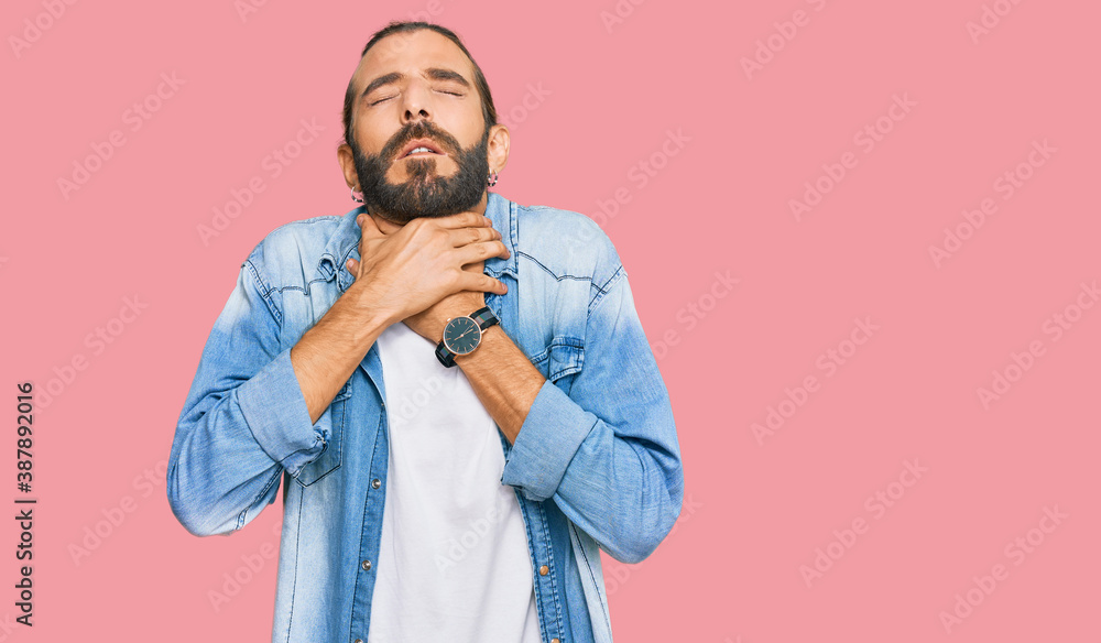 Attractive man with long hair and beard wearing casual denim jacket shouting suffocate because painful strangle. health problem. asphyxiate and suicide concept. Attractive man with long hair and beard wearing casual denim jacket shouting suffocate because painful strangle. health problem. asphyxiate and suicide concept.