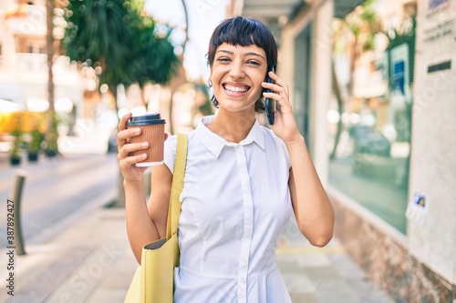 Young woman with short hair smiling happy outdoors speaking on the phone