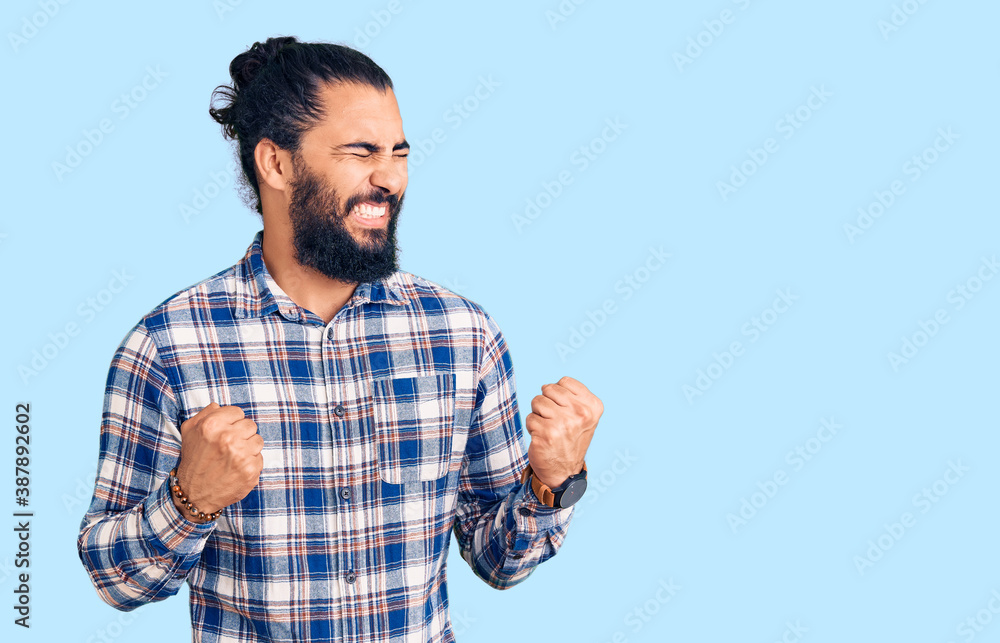 Young arab man wearing casual clothes excited for success with arms raised and eyes closed celebrating victory smiling. winner concept. Young arab man wearing casual clothes excited for success with arms raised and eyes closed celebrating victory smiling. winner concept.