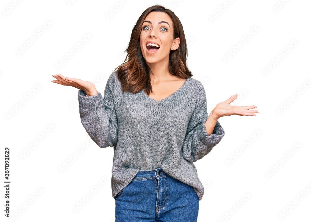 Young brunette woman wearing casual winter sweater celebrating victory with happy smile and winner expression with raised hands Young brunette woman wearing casual winter sweater celebrating victory with happy smile and winner expression with raised hands