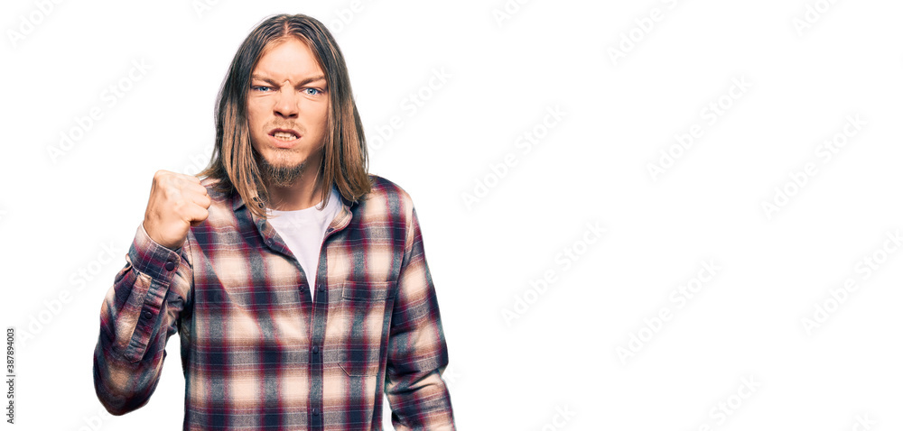 Handsome caucasian man with long hair wearing hipster shirt angry and mad raising fist frustrated and furious while shouting with anger. rage and aggressive concept. Handsome caucasian man with long hair wearing hipster shirt angry and mad raising fist frustrated and furious while shouting with anger. rage and aggressive concept.