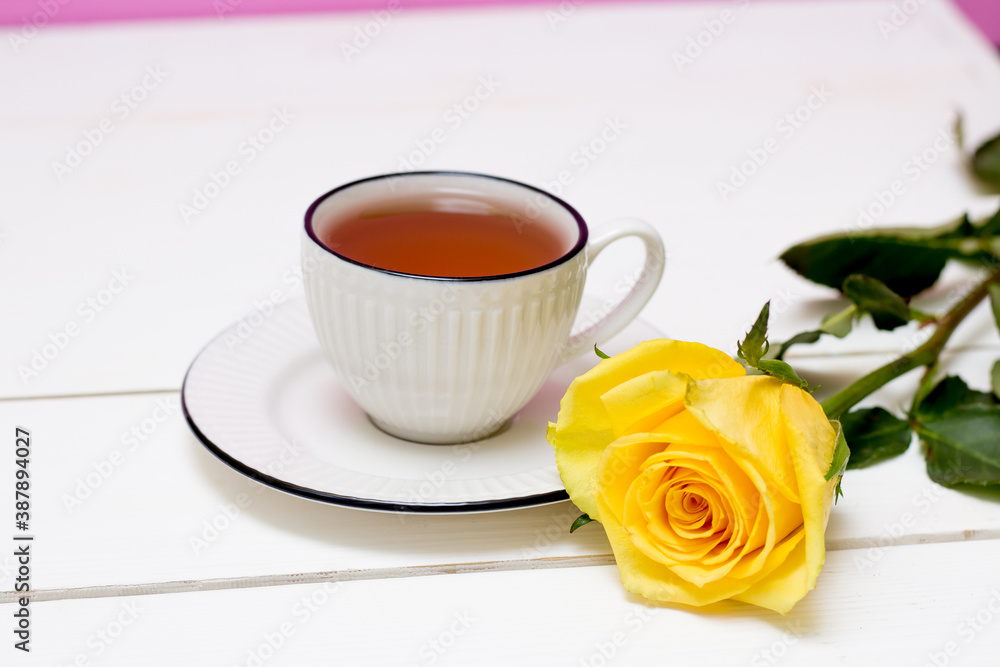 A cup of tea and oatmeal cookies. Yellow rose. Breakfast. Tea drinking. White wood background and pink wall.
