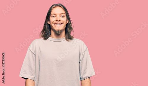 Handsome caucasian man with long hair wearing casual clothes with a happy and cool smile on face. lucky person.
