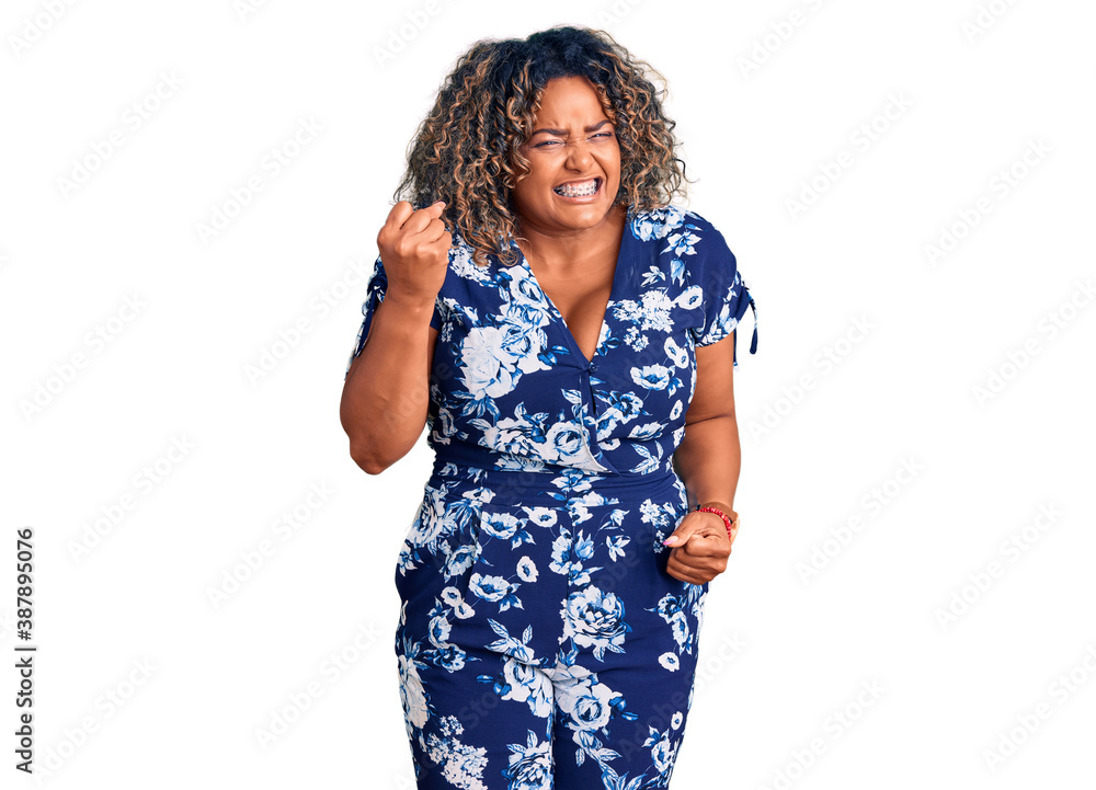 Young african american plus size woman wearing casual clothes angry and mad raising fist frustrated and furious while shouting with anger. rage and aggressive concept. Young african american plus size woman wearing casual clothes angry and mad raising fist frustrated and furious while shouting with anger. rage and aggressive concept.