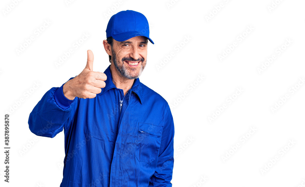 Middle age handsome man wearing mechanic uniform doing happy thumbs up gesture with hand. approving expression looking at the camera showing success.