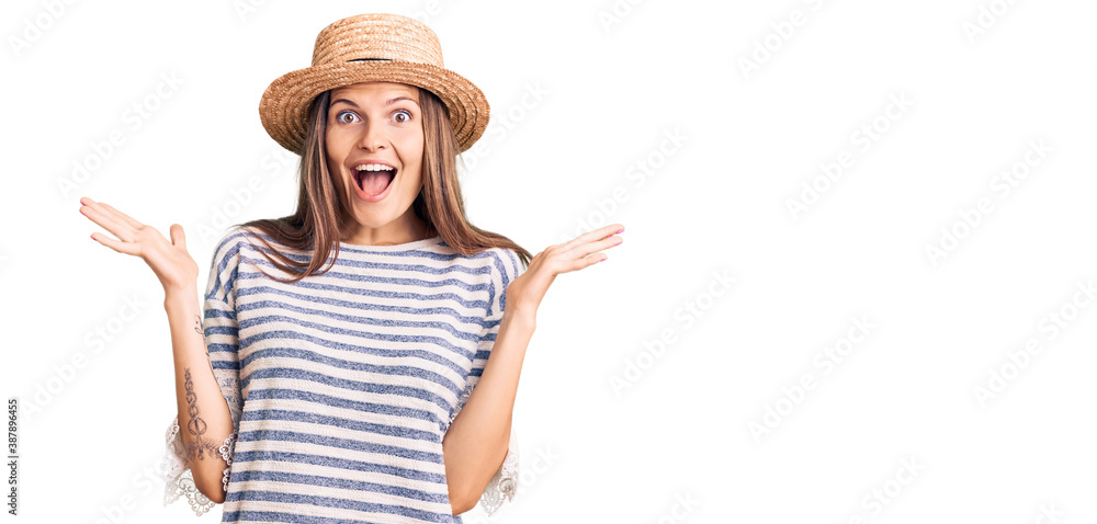 Beautiful caucasian woman wearing summer hat celebrating crazy and amazed for success with arms raised and open eyes screaming excited. winner concept
