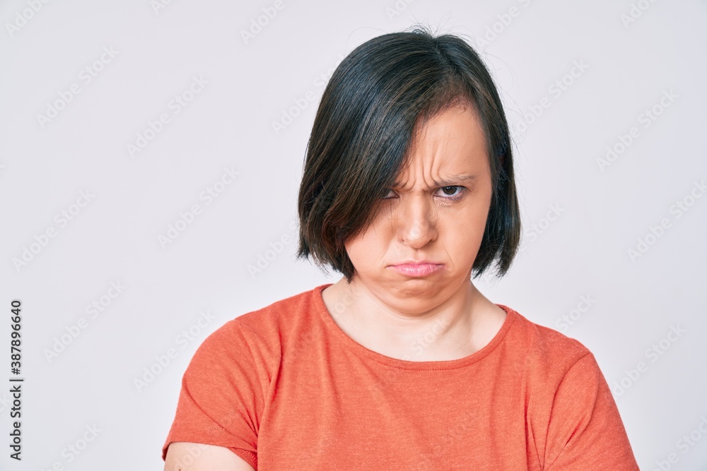 Brunette woman with down syndrome wearing casual clothes skeptic and nervous, disapproving expression on face with crossed arms. negative person. Brunette woman with down syndrome wearing casual clothes skeptic and nervous, disapproving expression on face with crossed arms. negative person.