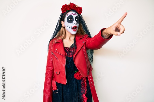 Woman wearing day of the dead costume over white pointing with finger surprised ahead  open mouth amazed expression  something on the front