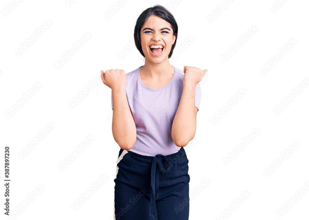 Brunette teenager girl wearing casual clothes celebrating surprised and amazed for success with arms raised and open eyes. winner concept. Brunette teenager girl wearing casual clothes celebrating surprised and amazed for success with arms raised and open eyes. winner concept.