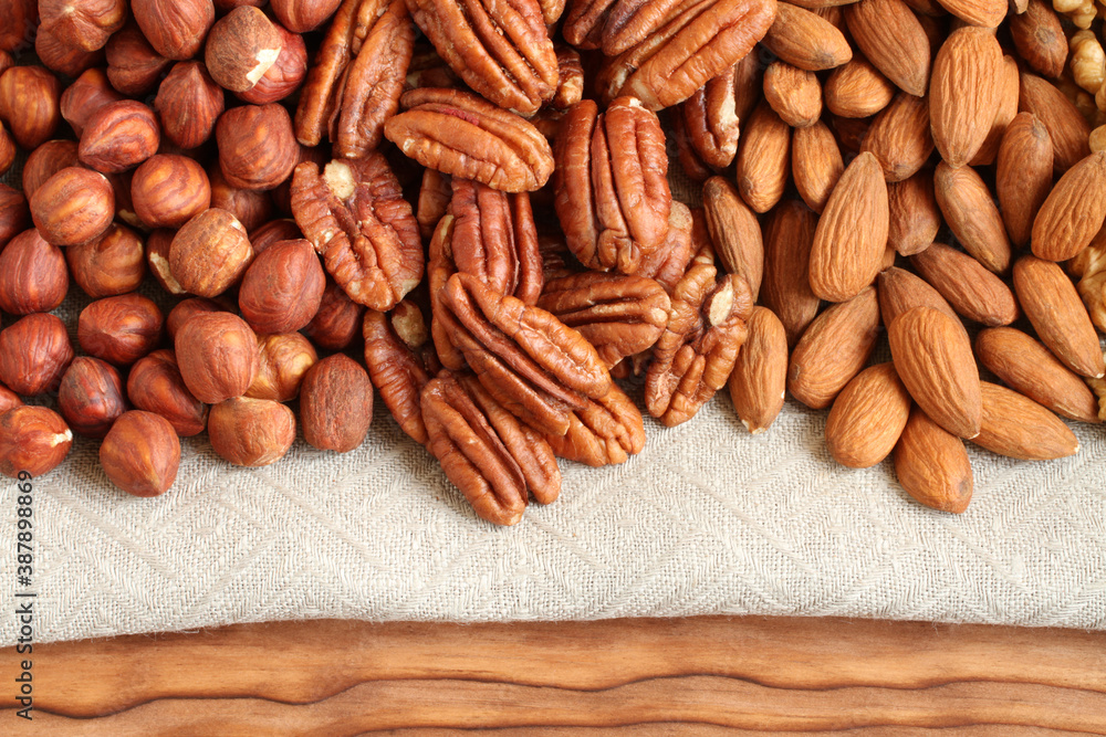 Raw peeled hazelnuts, pecans and almonds on a linen cloth. Closeup. Macro Raw peeled hazelnuts, pecans and almonds on a linen cloth. Closeup. Macro