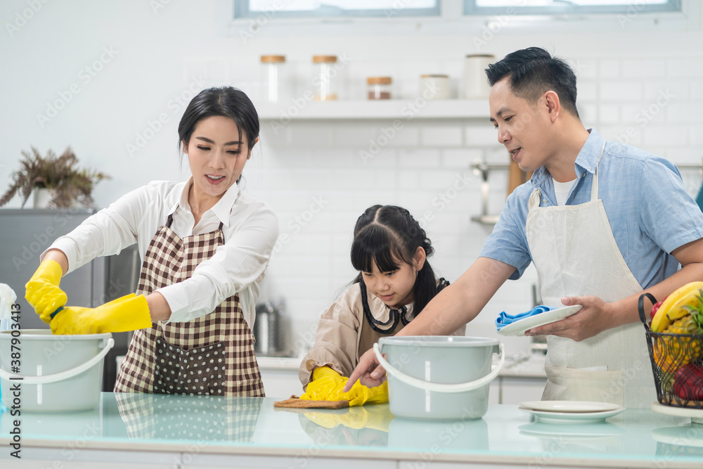 Asian young family teaching their daughter to clean kitchen counter. Asian young family teaching their daughter to clean kitchen counter.