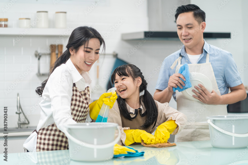 Asian young family teaching their daughter to clean kitchen counter. Asian young family teaching their daughter to clean kitchen counter.