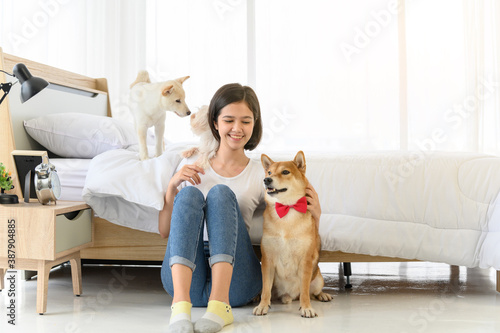 Canvas Print Young Asian woman relaxing and playing with three dogs (brown shiba inu, white shiba puppy and white maltese)in bedroom at home, Cheerful and nice couple with people and pet