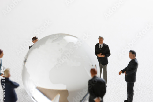 地球儀を見てミーティングをするビジネスマンのミニチュア