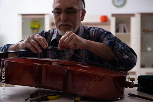 Obraz na plátně Senior male repairman repairing musical instruments at home