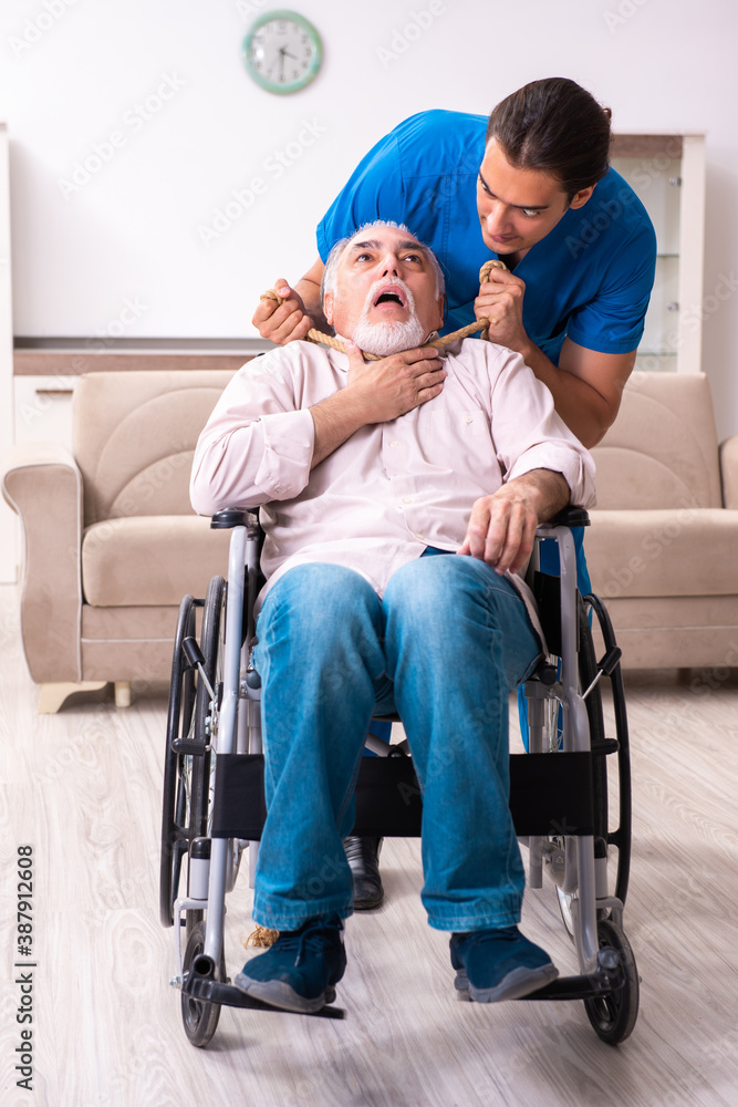 Old man in wheel-chair and young bad caregiver indoors Old man in wheel-chair and young bad caregiver indoors
