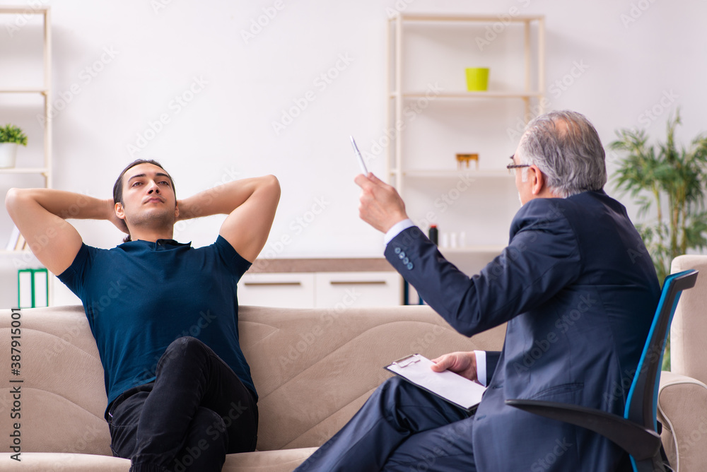 Young man visiting old male psychologist Young man visiting old male psychologist