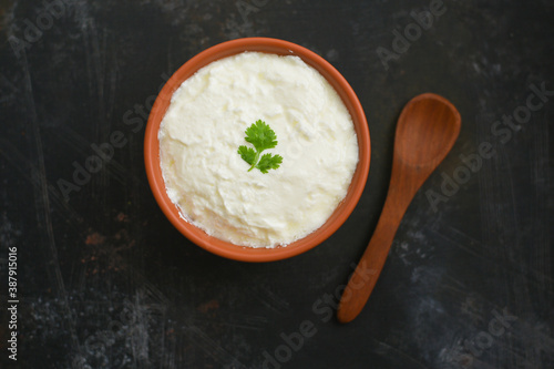 Bowl of homemade sour cream curd yogurt Dahi fresh herbs curry leaf Kerala, India. Dairy product obtained by coagulating milk a process curdling. probiotic food. tasty curd rice curry spices