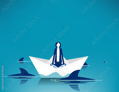 Businesswoman sitting on paper boat surrounded by sharks photo