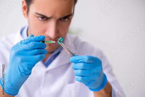 Young male lab assistant in drug synthesis concept