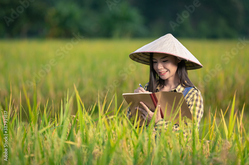 happy asian female Write notes in rice fields