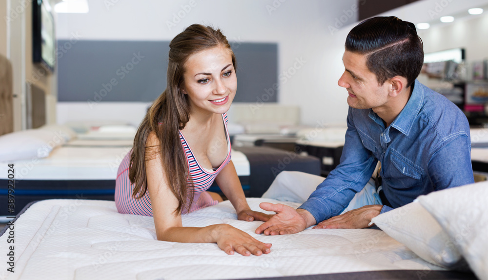 Obraz premium Happy family couple choosing mattress in furniture store