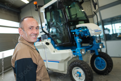 portrait of male mechanic agricultural vehicle in background