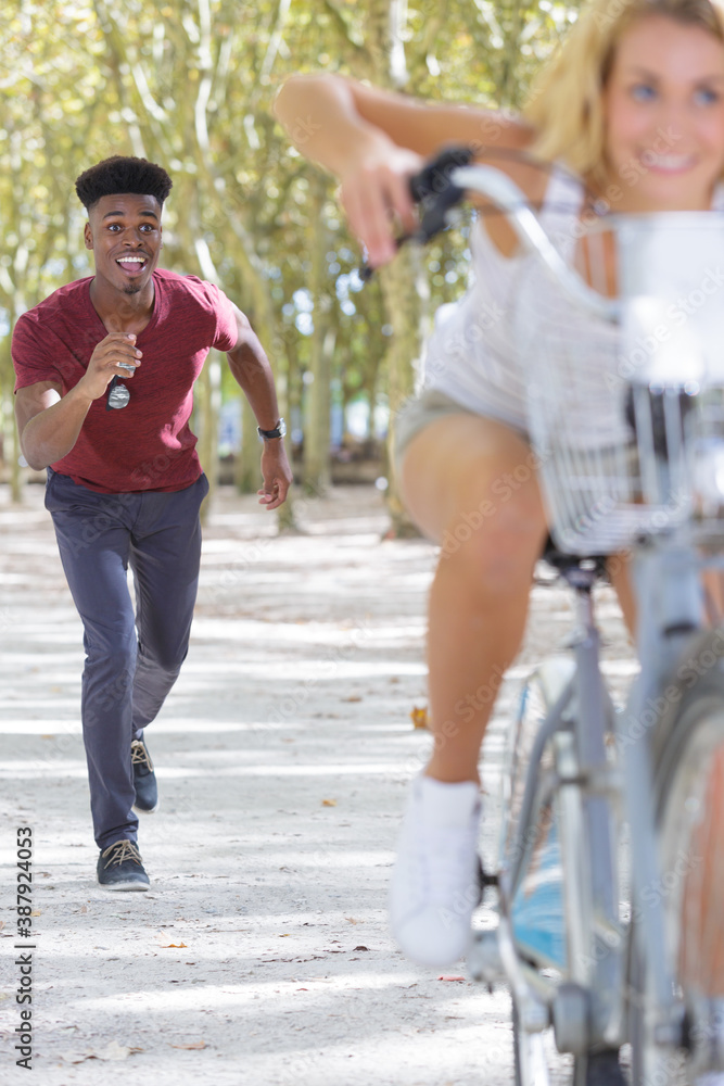 Obraz premium happy couple running behind woman riding bicycle