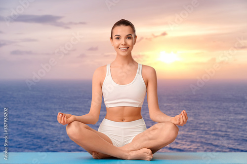 Beautiful young woman practicing yoga at resort