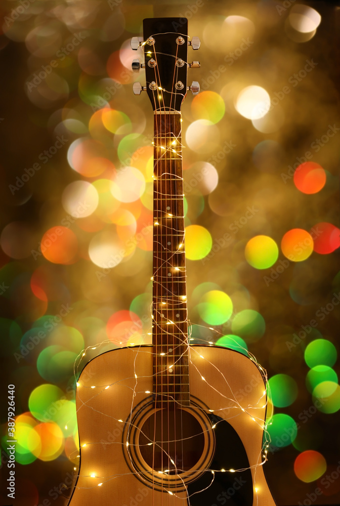 Guitar with glowing Christmas garland against blurred lights
