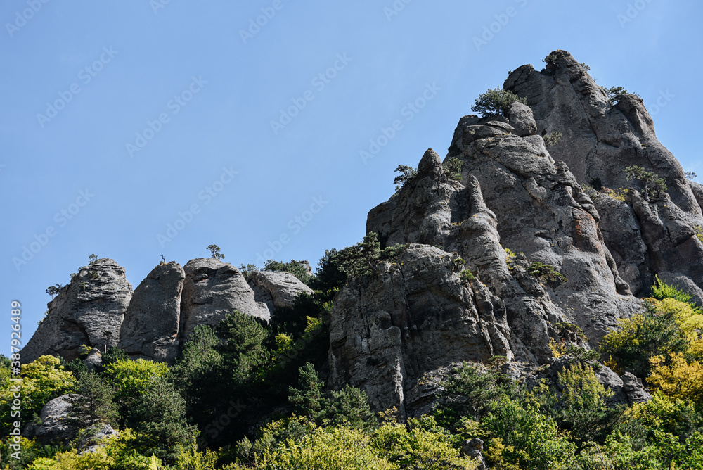 Fototapeta premium Stone hills and mountains with green trees and bushes against the blue sky