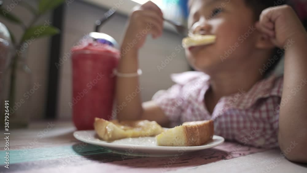 Asian boy about 4 years old eating sugar toast and sweet juice by himself Asian boy about 4 years old eating sugar toast and sweet juice by himself