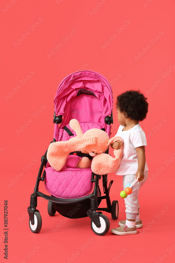 Cute African-American baby with stroller on color background Cute African-American baby with stroller on color background