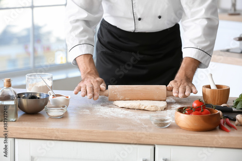 Mature male chef making dough for pizza in kitchen
