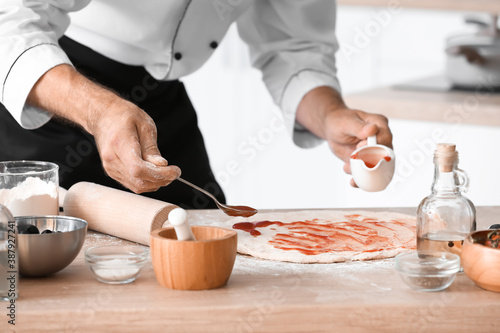 Mature male chef cooking tasty pizza in kitchen, closeup