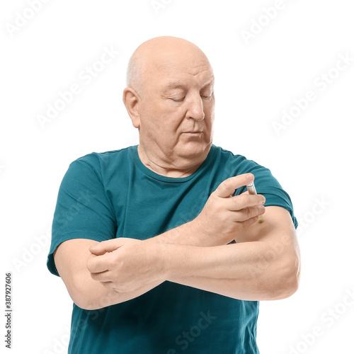 Senior diabetic man giving himself insulin injection on white background