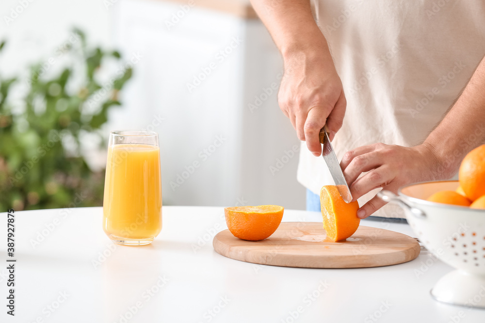 Man cutting orange in kitchen, closeup Man cutting orange in kitchen, closeup