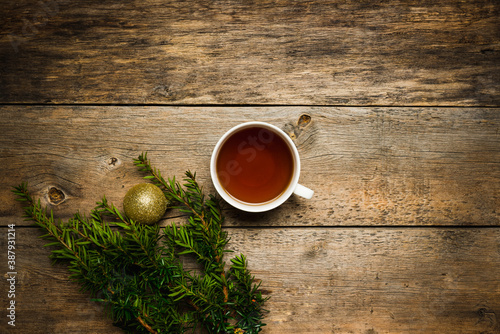 Christmas hygge background with cup of tea, pine branches and christmas ball on the wooden background. Selective focus. Shallow depth of field. 