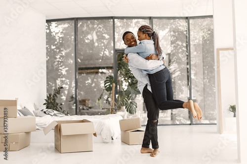 Young couple moving in to new home together. African american couple with cardboard boxes. © prostooleh