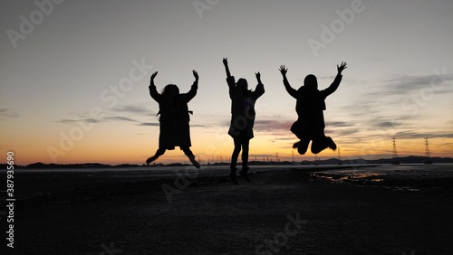 silhouettes of people jumping on the beach