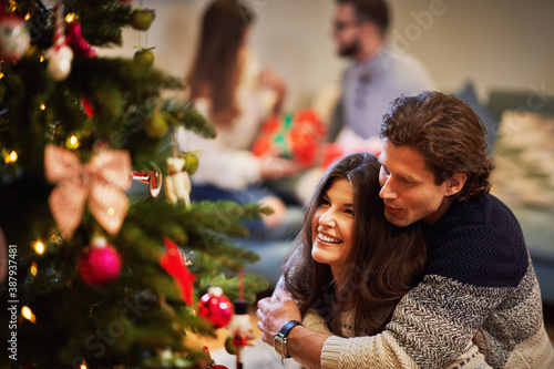 Adult couples having fun over Christmas tree © Kalim