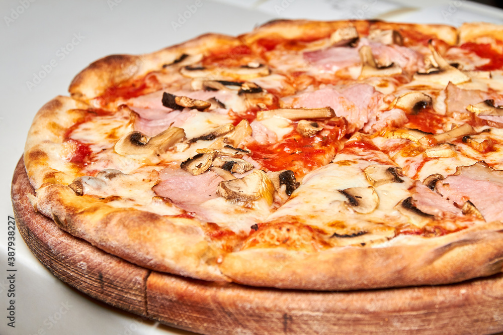 Fresh pizza with bacon, tomatoes, mushrooms and cheese on a light background. Close-up, selective focus