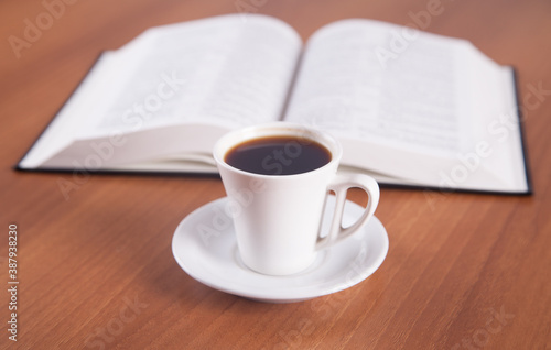 Book and coffee are isolated on a wooden background.