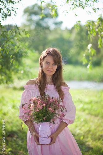 beautiful girl in a pink dress walks with a bouquet of pink flowers, a photo session in a fairy-tale style at sunset © AKaltykova
