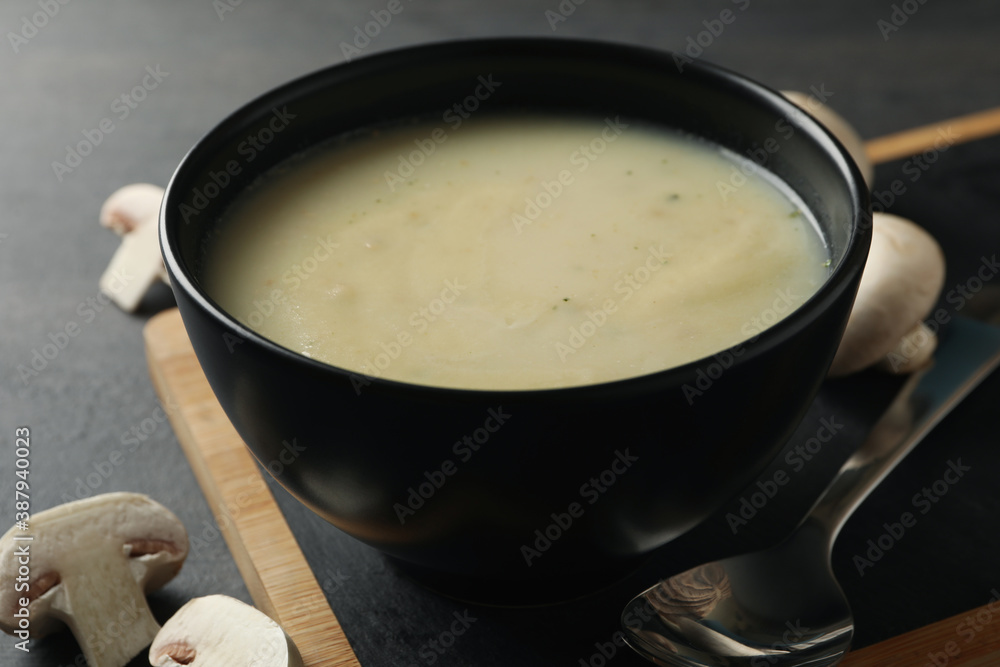 Concept of tasty lunch with bowl of mushroom soup on black background Concept of tasty lunch with bowl of mushroom soup on black background