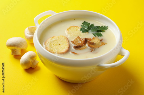 Bowl of tasty mushroom soup on yellow background