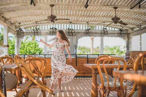 girl dancing in cafe on the beach. young slim beautiful woman on sunset beach  playful  dancing  running  bohemian outfit  indie style  summer vacation  sunny  having fun  positive mood  romantic