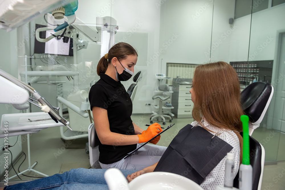 Professional dentist with clipboard talking or recording diagnosis with patient before treatment Professional dentist with clipboard talking or recording diagnosis with patient before treatment