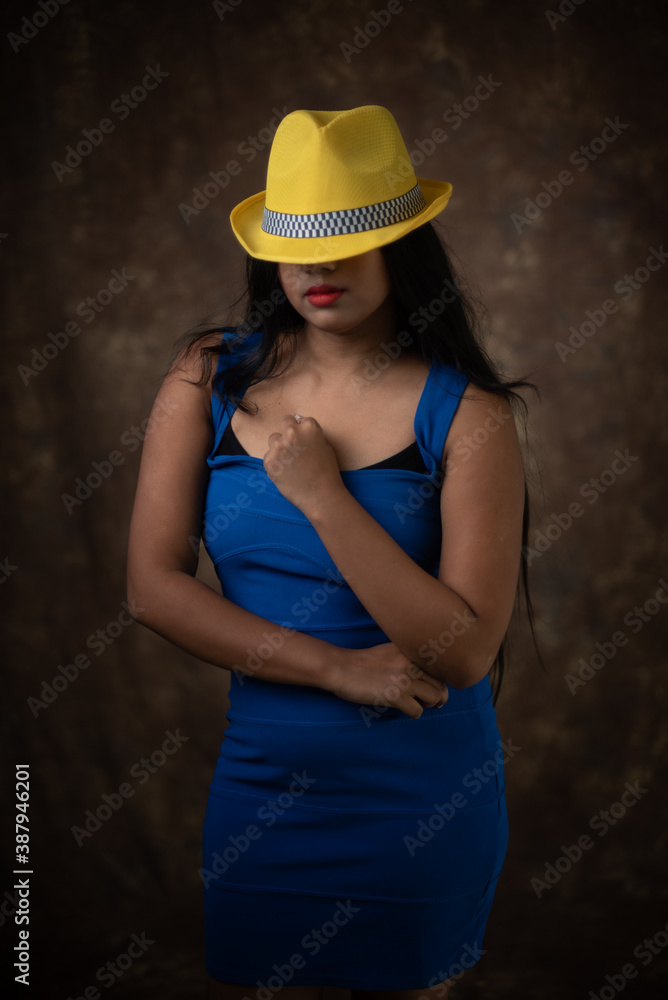 Studio portrait of an young Indian girl in blue western dress and yellow hat in front of textured background. Fashion portrait photography Studio portrait of an young Indian girl in blue western dress and yellow hat in front of textured background. Fashion portrait photography