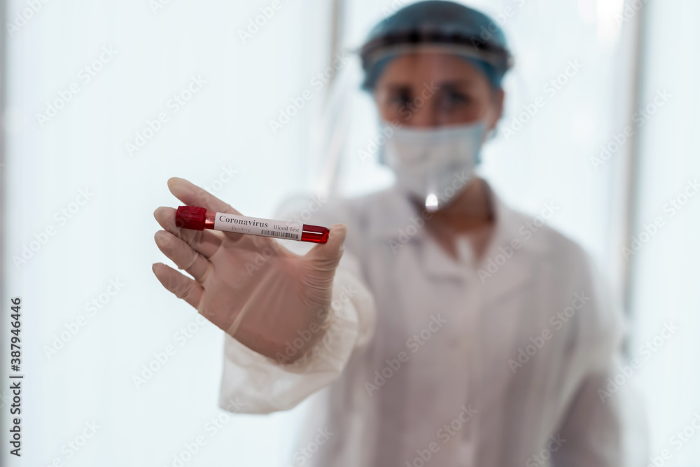 female nurse wearing protective cloth holding a tube with test blood for diagnostic on covid19 female nurse wearing protective cloth holding a tube with test blood for diagnostic on covid19